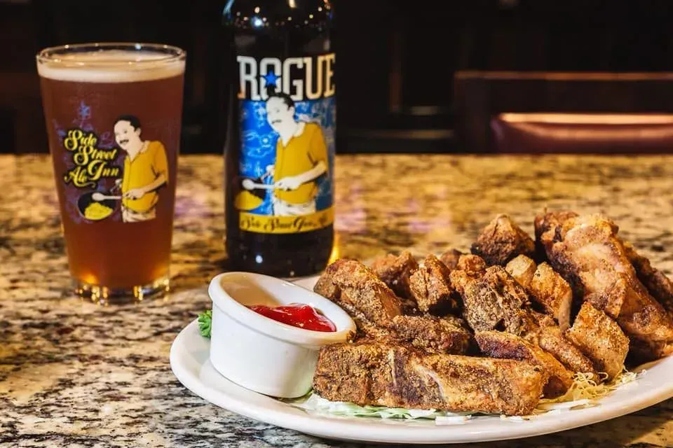 A plate of food and a bottle of beer on a table.