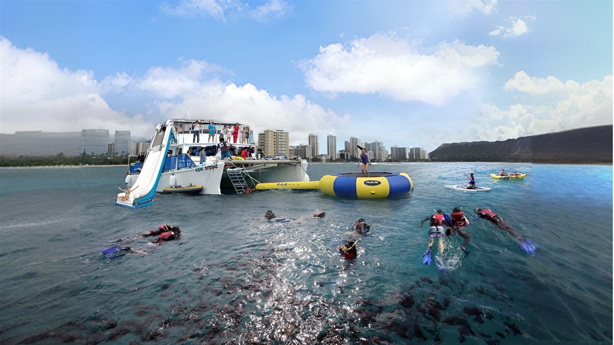 Catamaran with water slide, ocean trampoline, kayaks, and snorkelers off Waikiki