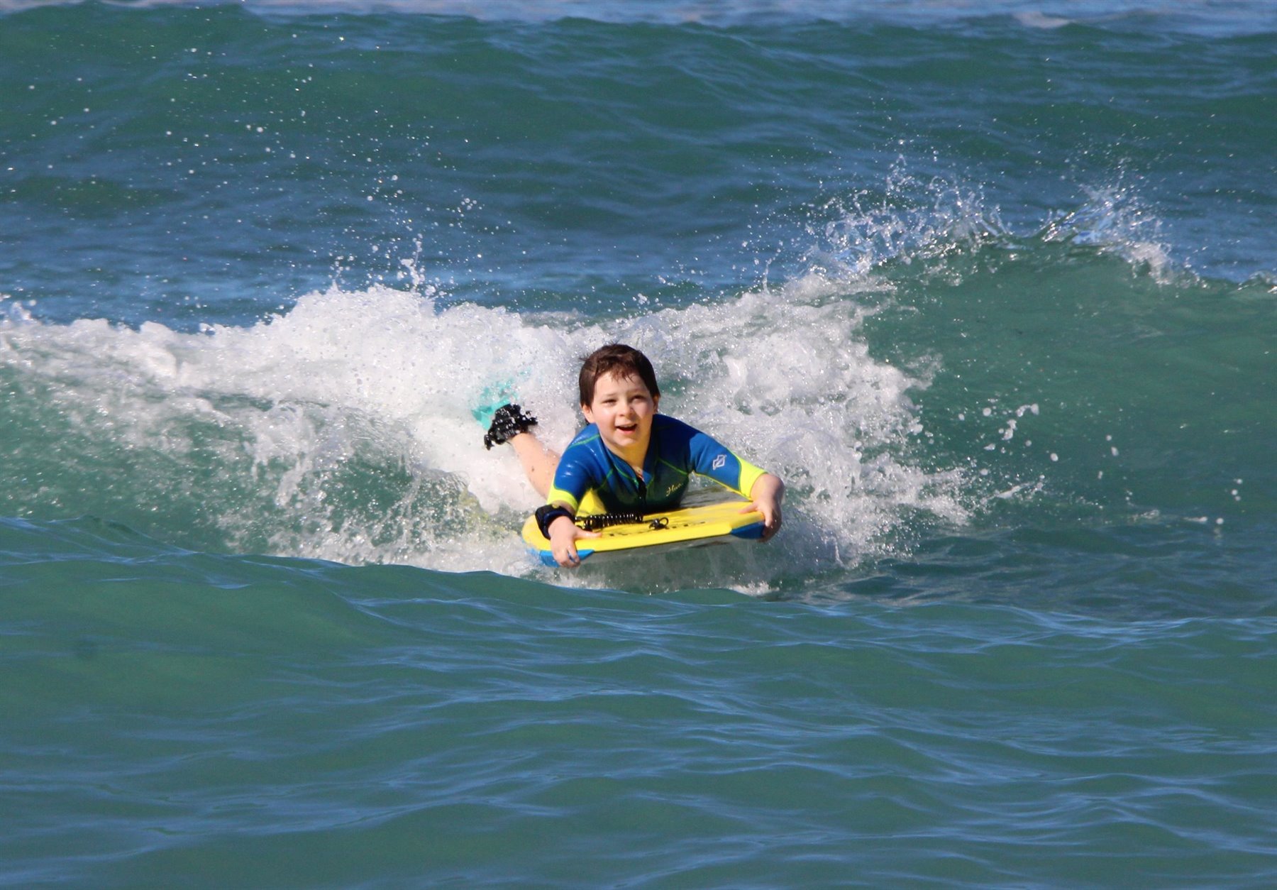Young bodyboarder riding the whitewater on a Hawaii wave