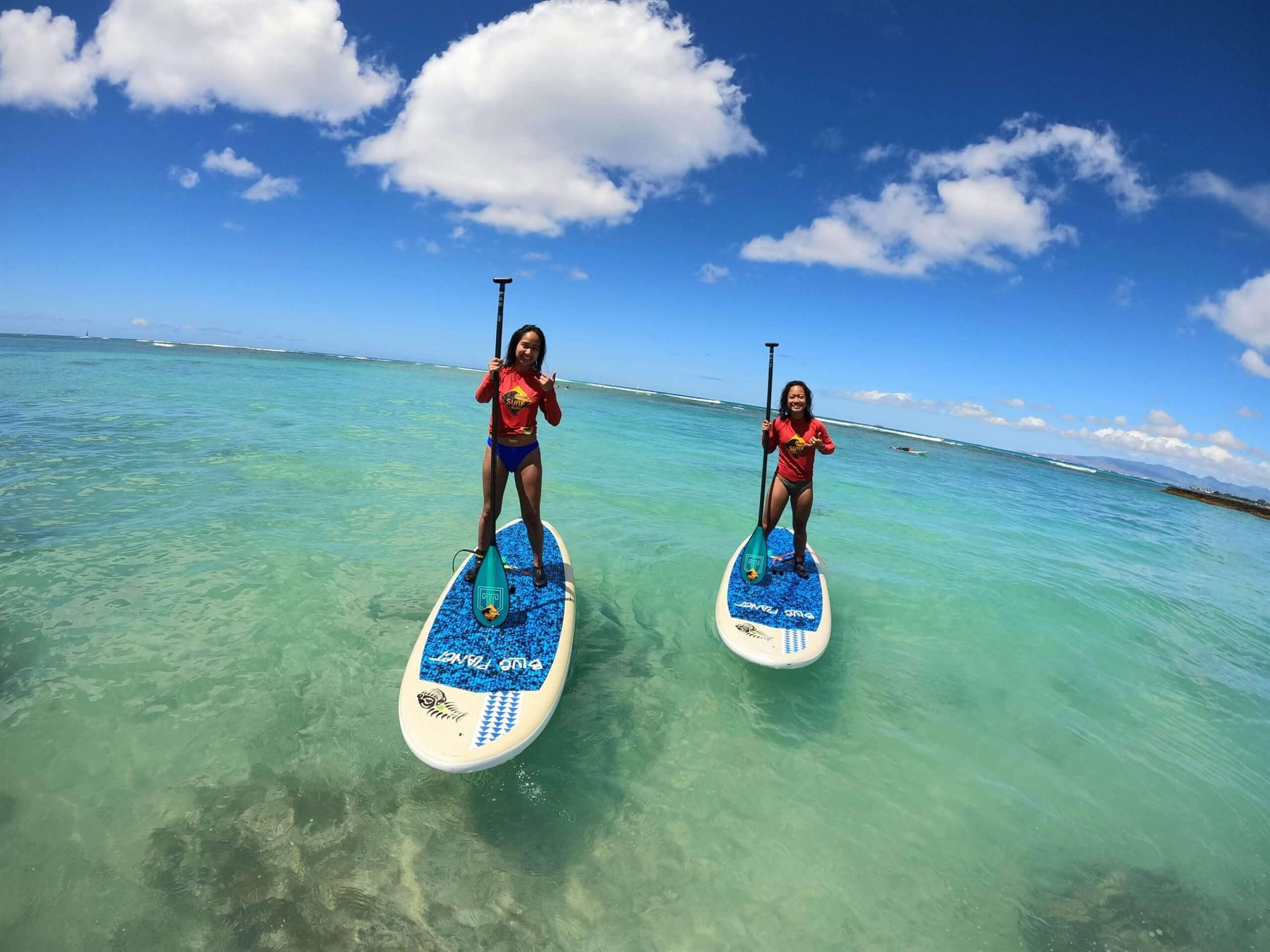 Two paddleboarders on clear turquoise water off Waikiki