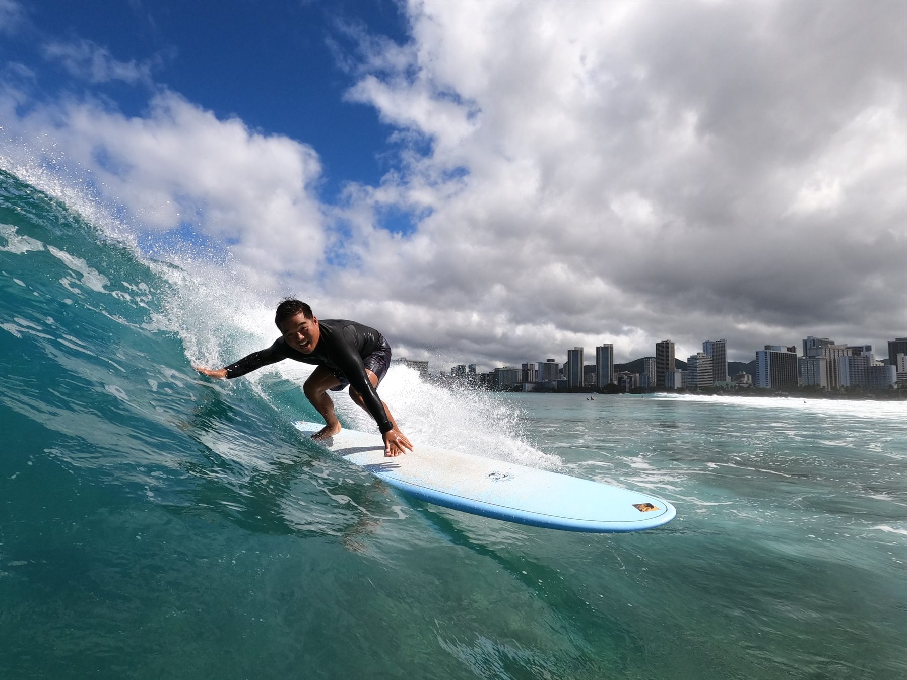 Surfer riding a wave off Waikiki with the Honolulu skyline behind
